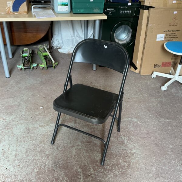 Black metal folding garden chair for outdoor use in a garden setting.
