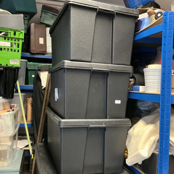 Lot of three large black plastic storage boxes for household use.