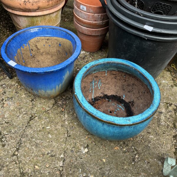 Vibrant blue glazed garden planters on display.