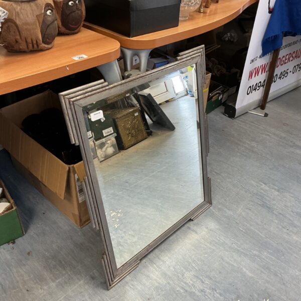 Vintage blue metal framed mirror leaning against a wall.