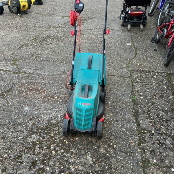 Green Bosch electric lawnmower in a garden setting.