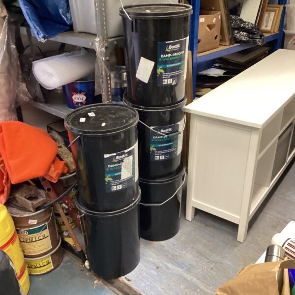 Five drums of Bostik damp-proofer and waterproofer in a storage area.