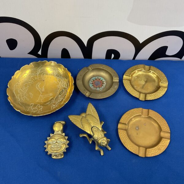 Vintage brass decorative dishes and fly vester on display.