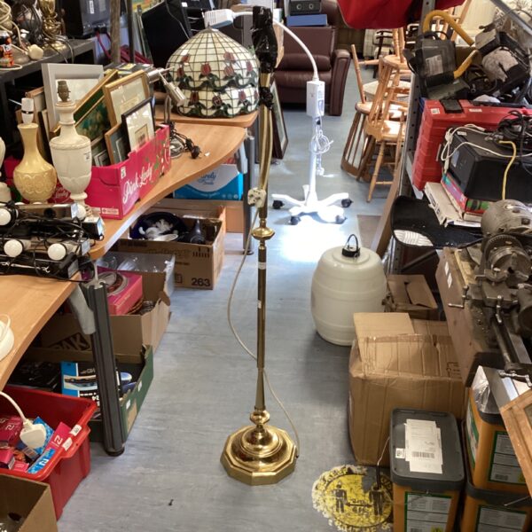 Vintage brass standard lamp in a cluttered room.
