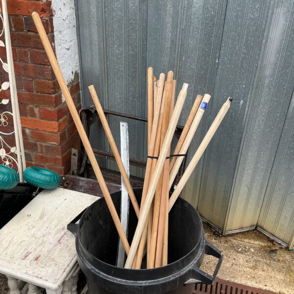 Lot of wooden broom handles for DIY projects and cleaning.