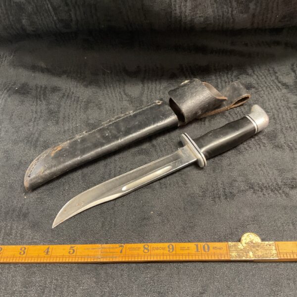 Vintage Buck sheath knife with leather sheath, classic American design.