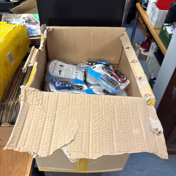 Large lot of new car MP3 players in an open cardboard box.