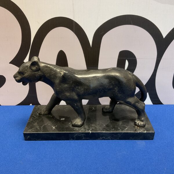 Detailed cast iron lioness sculpture on black marble base.