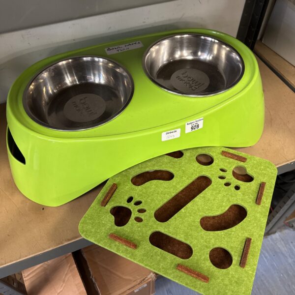 Cat feeding station with twin stainless steel bowls and a ball toy.