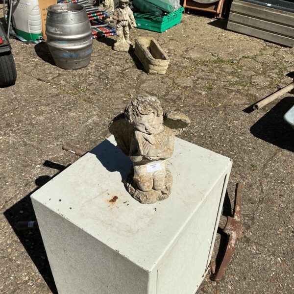 Vintage cherub garden ornament in a weathered garden setting.