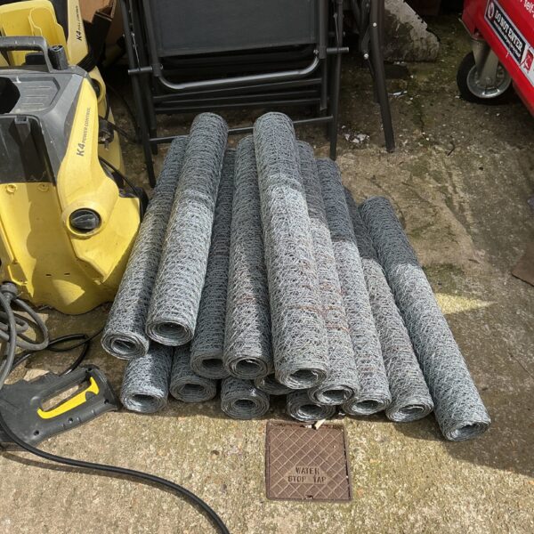Multiple rolls of galvanized steel chicken wire for garden fencing.