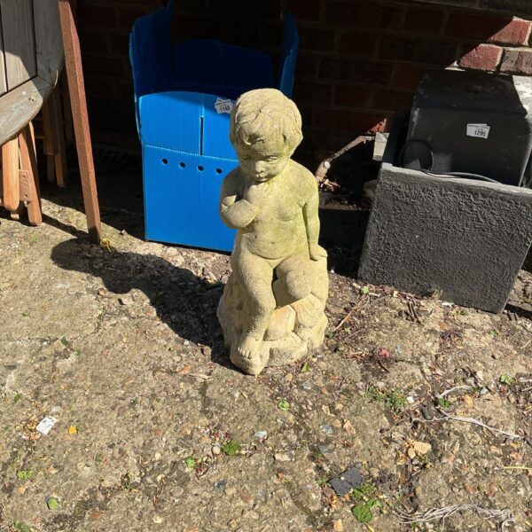 Vintage concrete child garden statue in a garden setting.