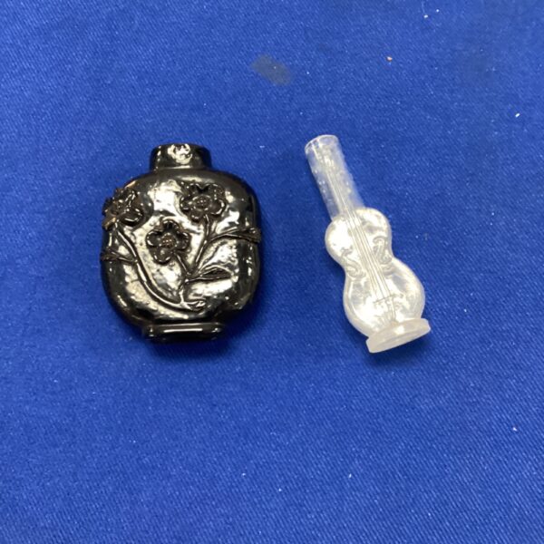 Antique Chinese obsidian snuff bottle with floral carvings.