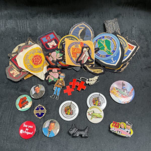 Vintage cloth and pin badge assortment featuring scouting emblems.