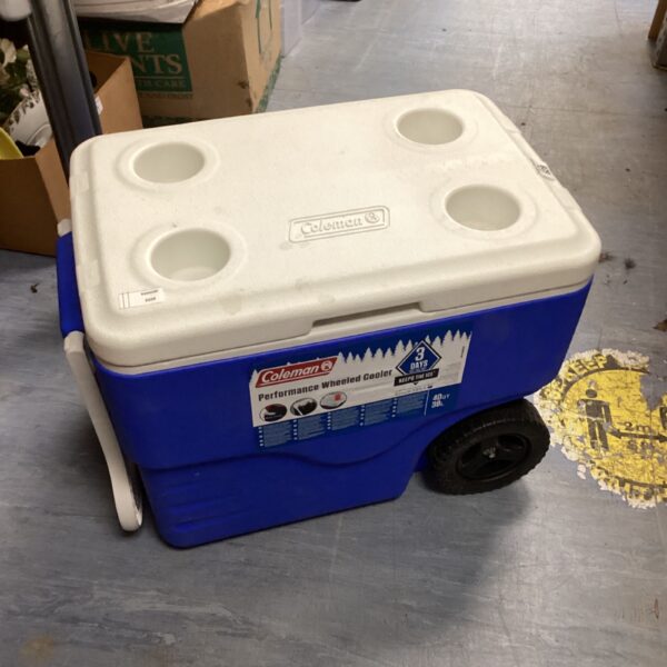 Blue Coleman cooler on wheels for camping and outdoor use.
