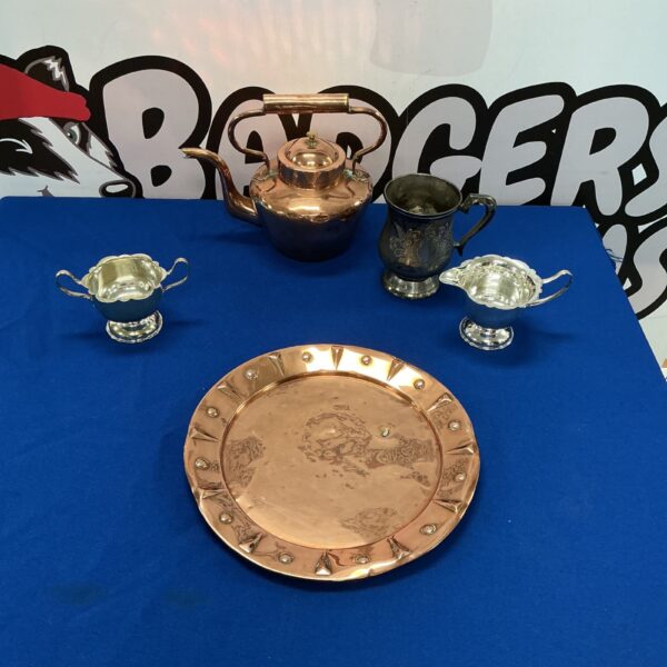 Vintage copper kettle and silverplate collection on display.
