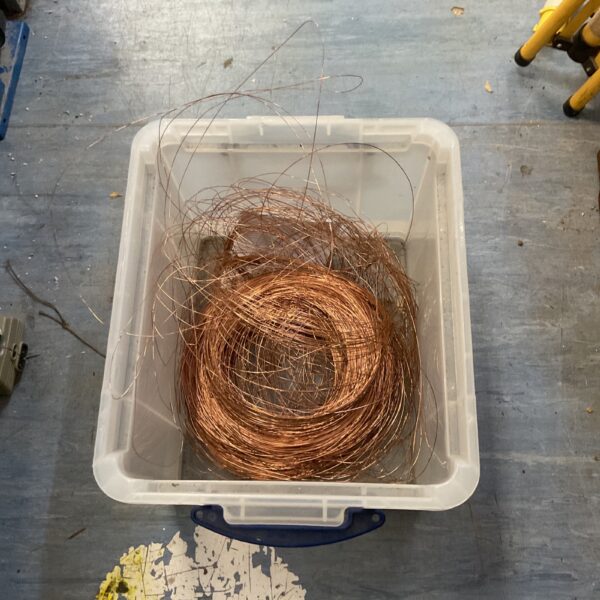 Bright copper wire scrap in a plastic container, ideal for DIY projects.