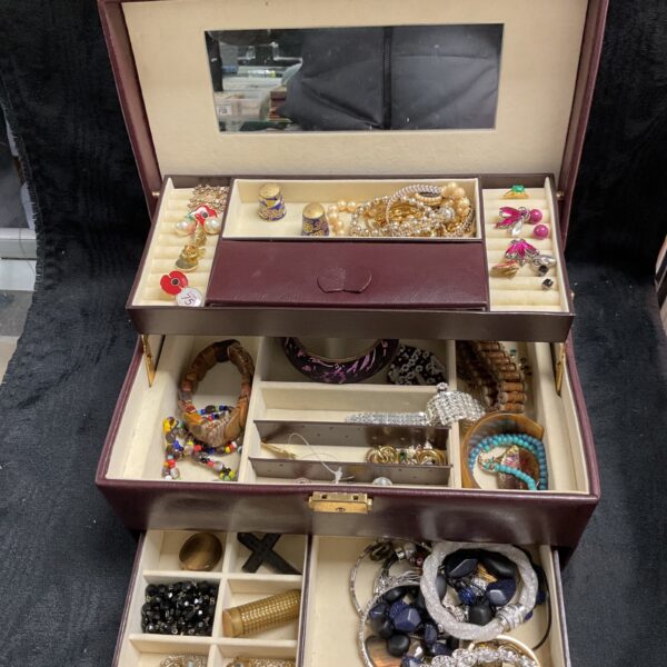 Large jewellery box filled with colourful costume jewellery pieces.