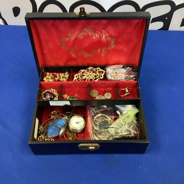 Open jewellery box filled with colourful costume jewellery and trinkets.