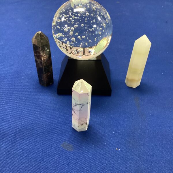 Illuminated crystal ball with decorative columns on a black base.