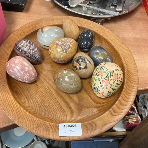 Decorative eggs displayed in a rustic wooden dish, folk art style.