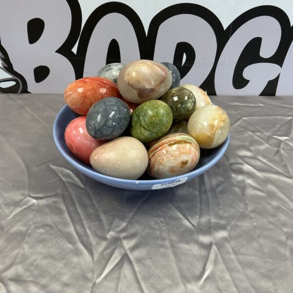 Collection of colourful decorative stone and marble eggs on display.