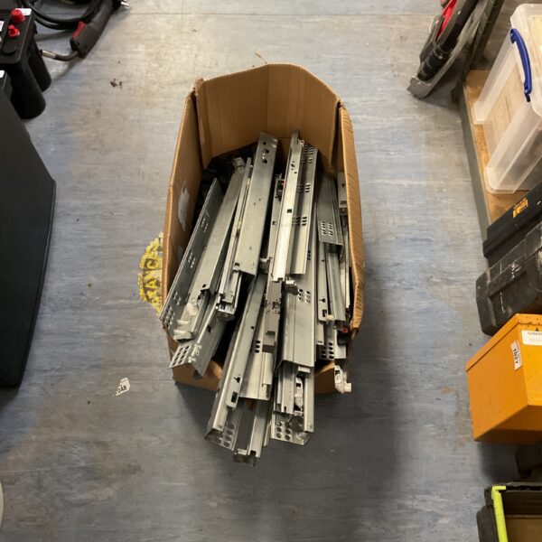 Metal drawer slides and cabinet runners in a cardboard box.