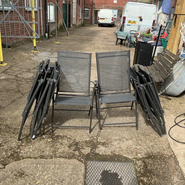 Eight mesh folding garden chairs in a garden setting.