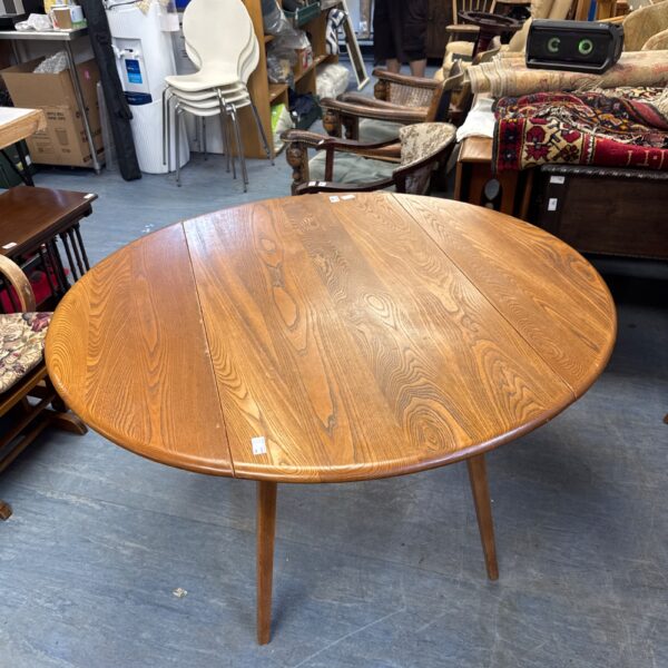 Vintage ercol drop leaf table in a cluttered antique shop.
