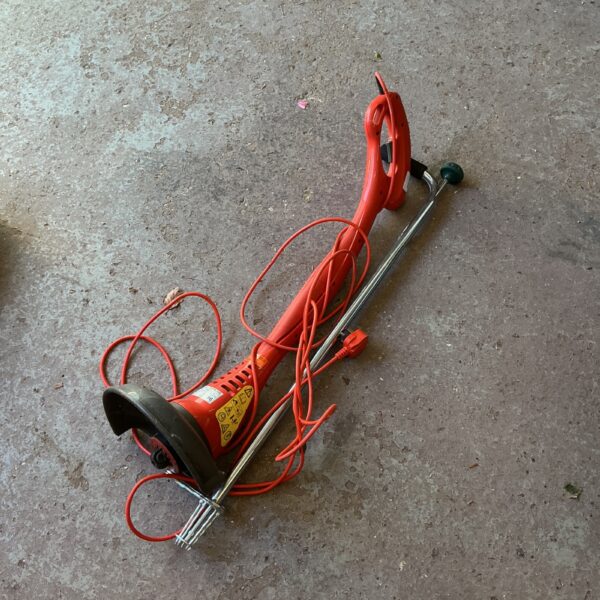 Flymo electric strimmer with weed puller attachment for garden maintenance.