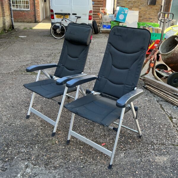 Pair of black folding garden chairs in a garden setting.