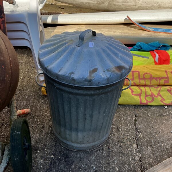 Vintage galvanised garden bin with lid, rustic outdoor storage.