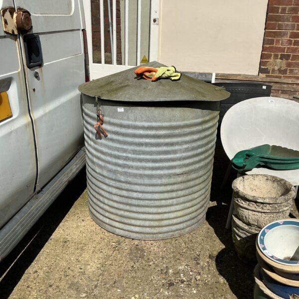 Weathered vintage galvanised water tank in an outdoor setting.