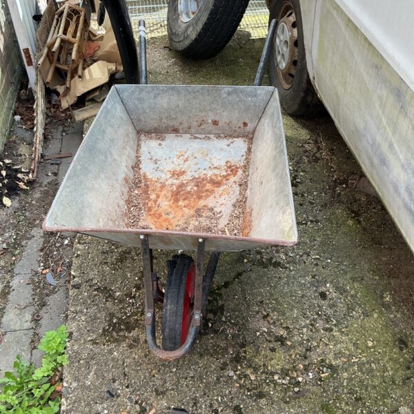 Vintage galvanised wheelbarrow in a garden setting.