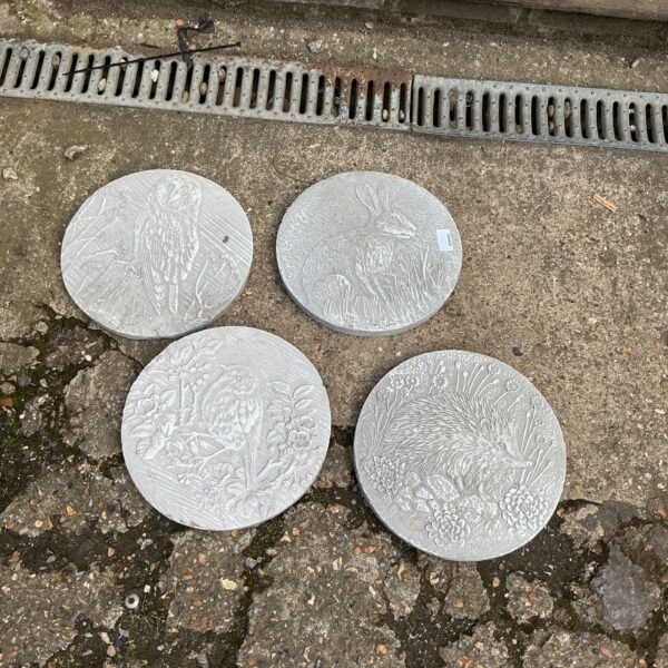 Set of four vintage garden animal plaques in a garden setting.