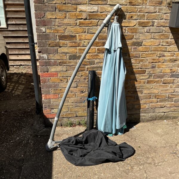 Blue garden cantilever parasol with base, showing signs of wear.