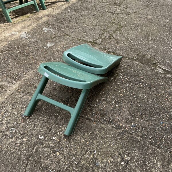 Green plastic garden chair footrest for outdoor comfort.
