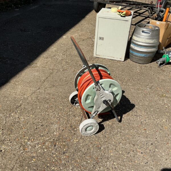Metal garden hose reel with a hose wound around it.