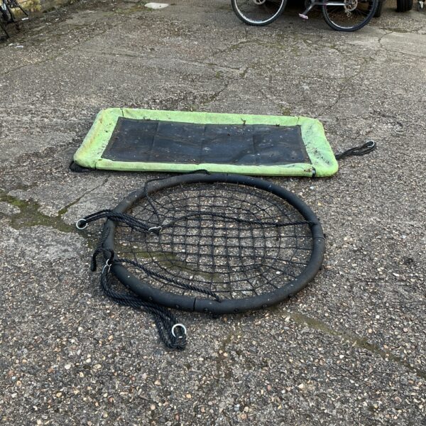 Woven garden swing seat with rope attachments, showing signs of wear.