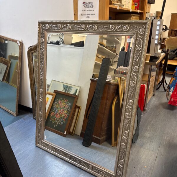 Large gilt framed bevelled mirror with ornate detailing.