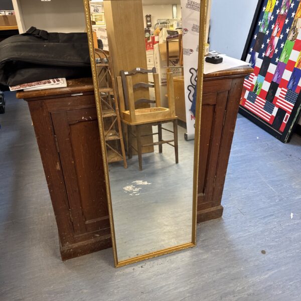 Ornate gilt framed mirror reflecting a room interior.