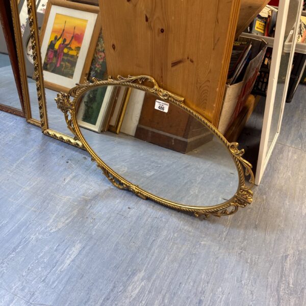 Ornate gilt framed oval mirror for vintage home decor.