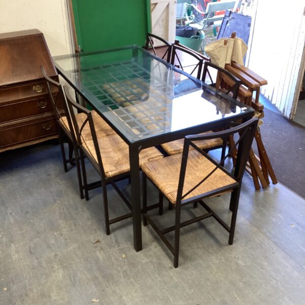 Vintage glass dining table with six cane chairs.