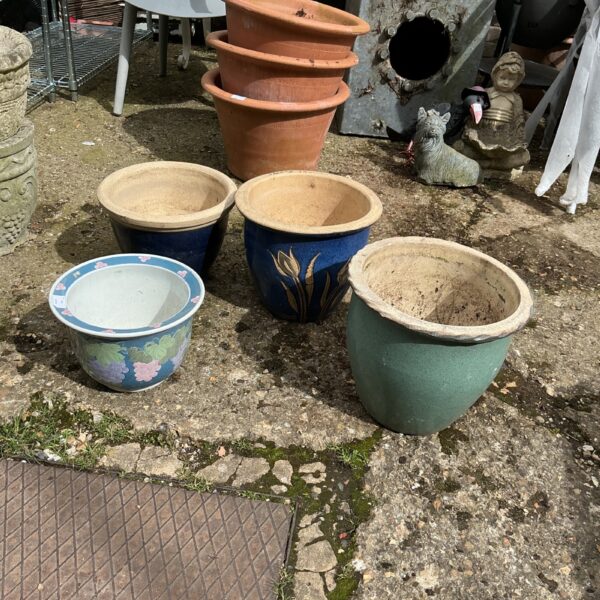 Set of four colourful glazed garden planters for outdoor use.