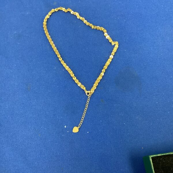 Delicate gold heart pendant necklace on a gold chain.