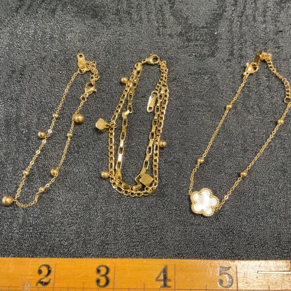 Gold plated bracelet set with floral pendant and beaded details.