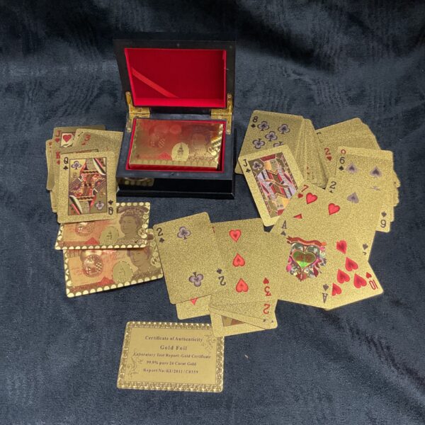 Display of gold playing cards and box on a dark surface.