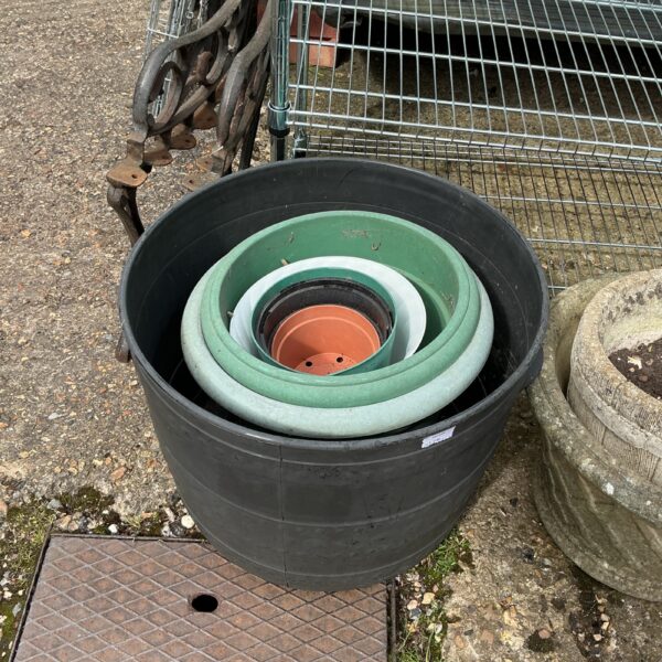 Graduated plastic garden planters stacked for storage in a garden setting.