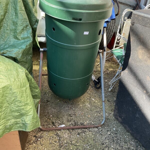 Green plastic compost bin with metal frame in garden.
