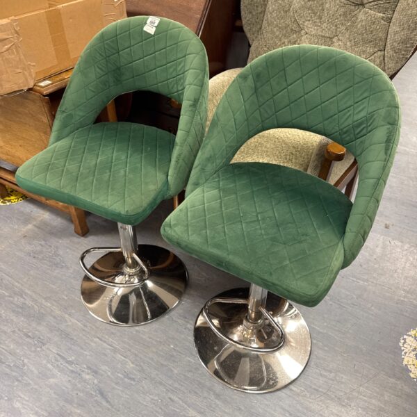 Pair of green velvet bar stools with chrome bases.
